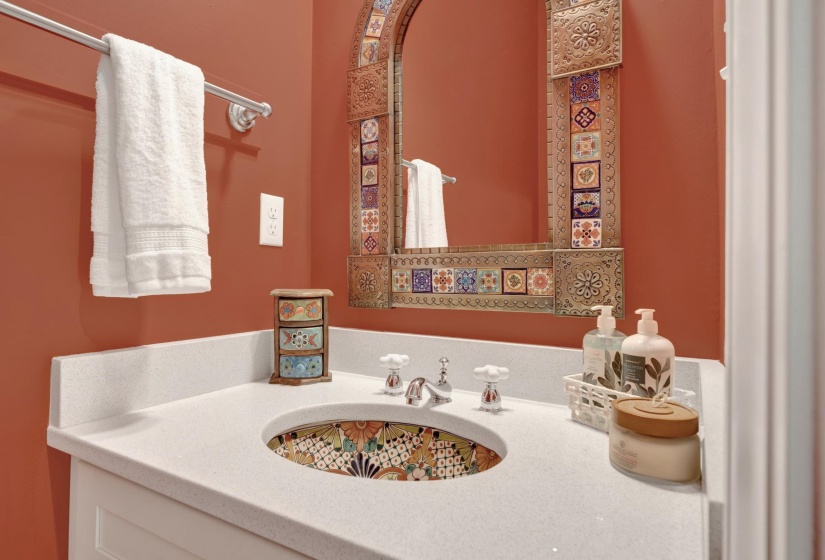 Bathroom vanity featuring a decorative ceramic basin, white countertop, and an ornate framed mirror