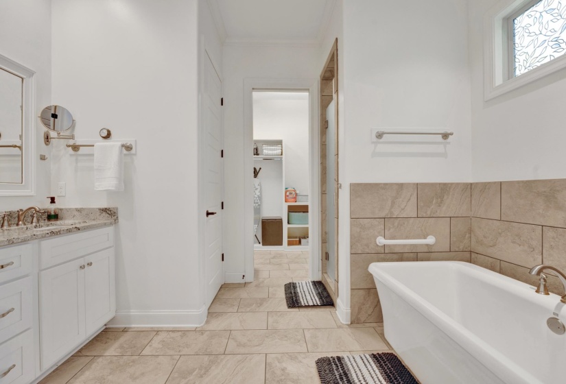 Bathroom featuring a freestanding soaking tub, tiled wainscoting, and large format floor tiles