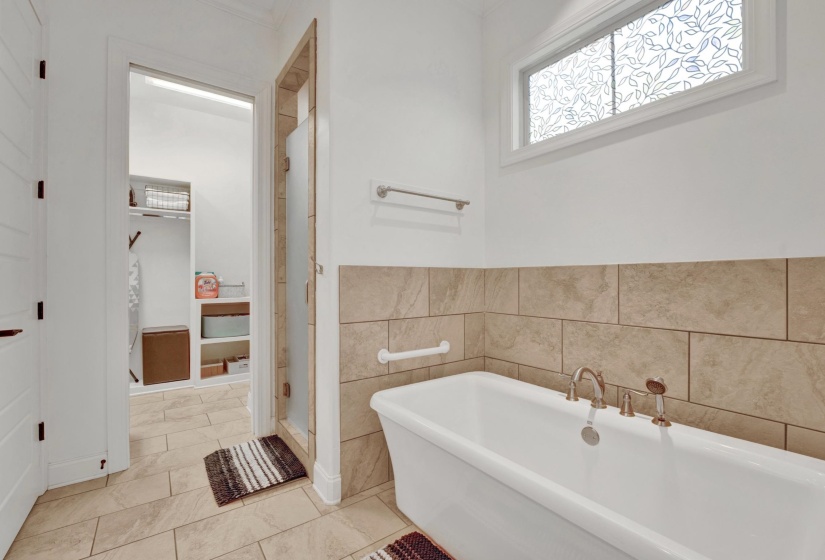 Bathroom featuring a freestanding bathtub with brushed nickel fixtures, tiled wainscoting, and a decorative frosted window