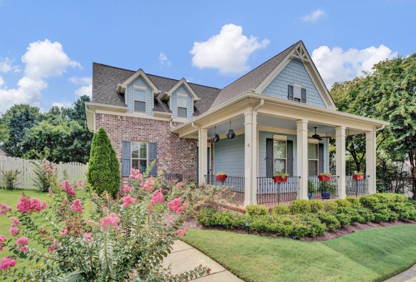 Brick and siding exterior with a covered porch, featuring decorative columns and iron railings