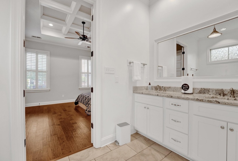 Dual vanity with stone countertop and integrated sinks, illuminated by a mirrored wall and overhead lighting