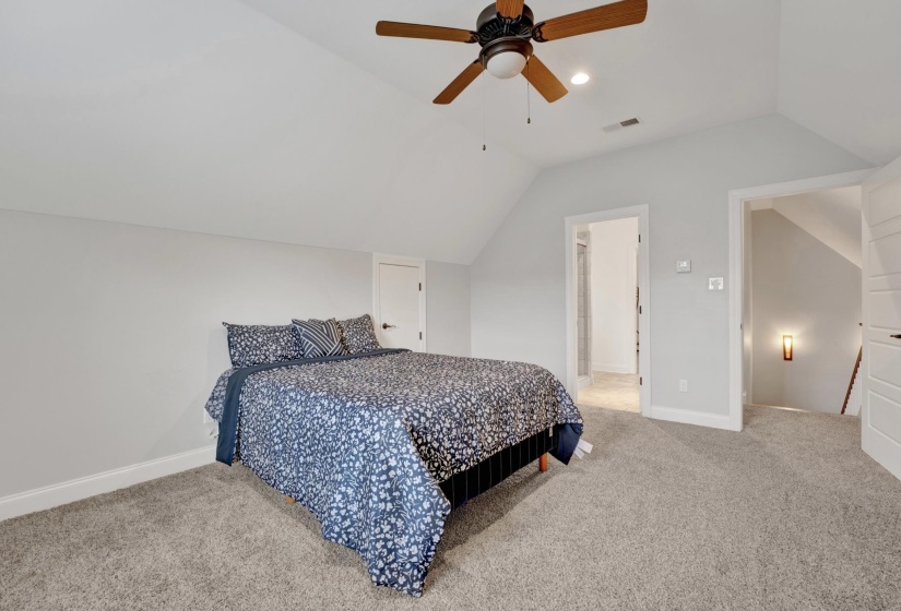Carpeted room with a vaulted ceiling and a ceiling fan with light fixture