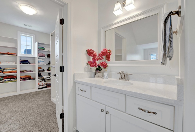 White vanity with a single basin, light-colored countertop, and a framed mirror above