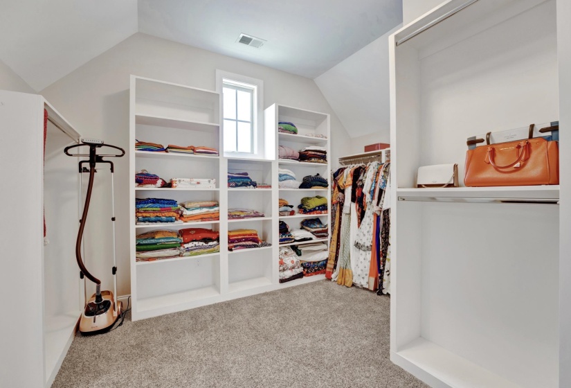 Custom built-in white shelving and hanging rods provide extensive storage