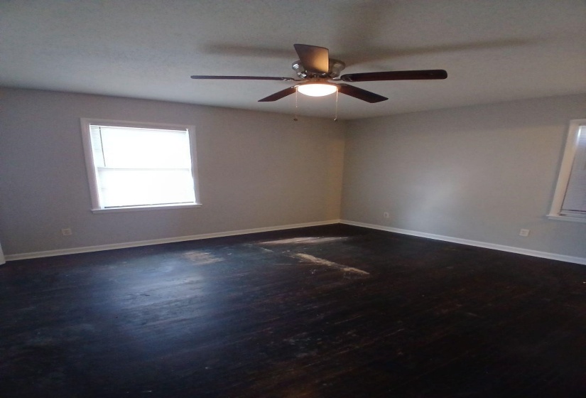 Interior room featuring dark wood-finish flooring, light neutral-toned walls, and white baseboards