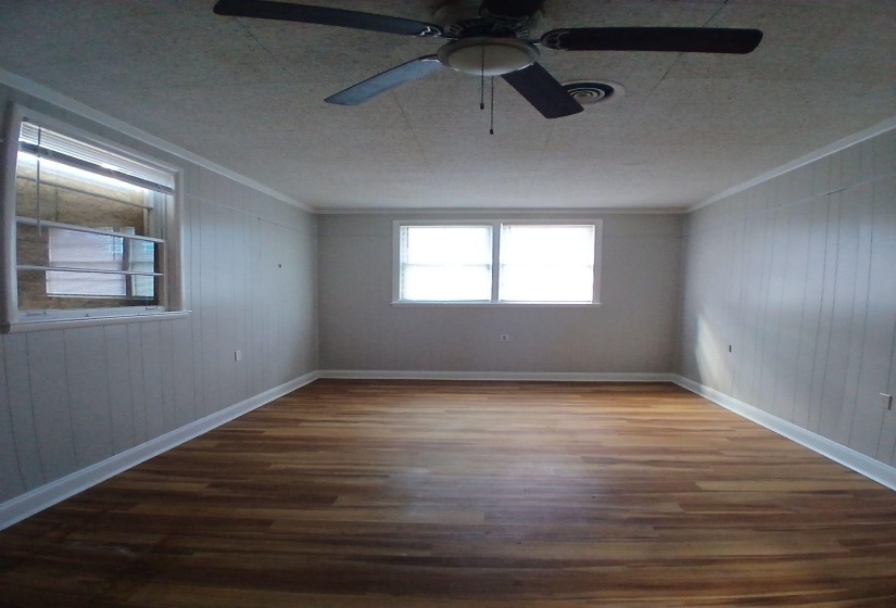 Room featuring wood-finish flooring, white baseboards, and board and batten paneling on walls