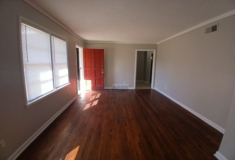 Spacious interior featuring rich wood-finish flooring, light gray walls, and white crown molding