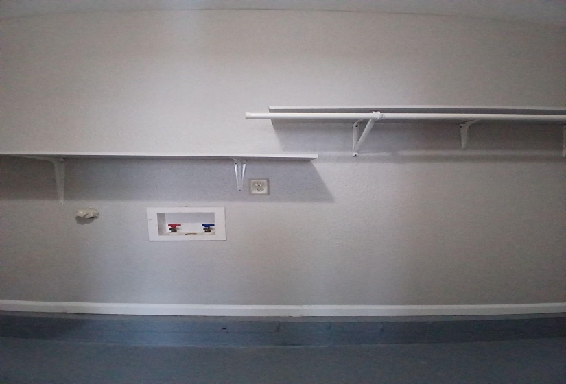 Laundry connections with hot and cold water hookups, multiple wall-mounted shelves, and a clothes hanging rod