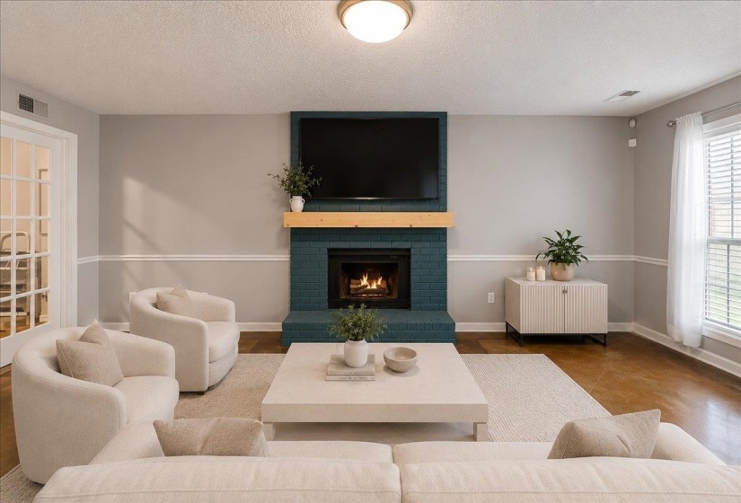 Living area featuring a teal brick fireplace with a wood mantel, light gray walls, crown molding, and wood-finish flooring
