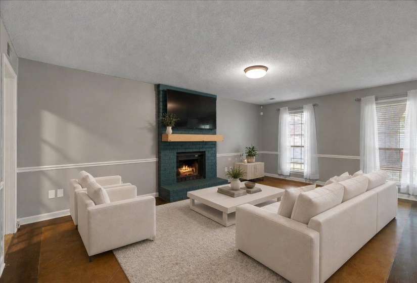 Living area featuring a teal brick fireplace with a wood mantle, multiple windows with blinds, crown molding, and wood-finish flooring