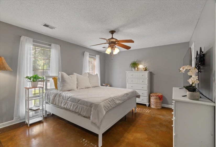 Spacious room featuring rich wood-finish flooring, neutral gray walls, and two windows with blinds