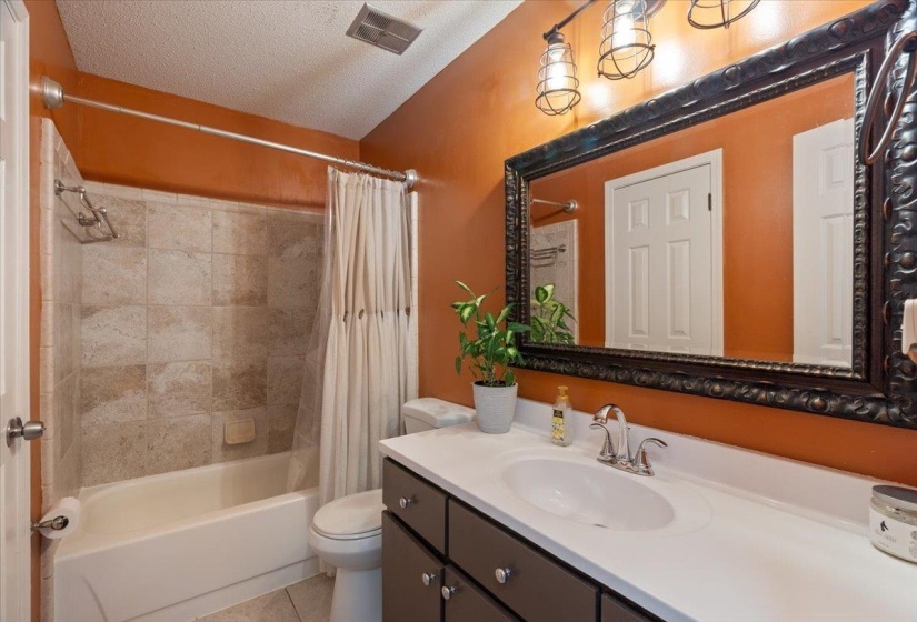 Full bathroom featuring a tub/shower combination with tile surround, a single vanity with an integrated sink, and an ornate framed mirror