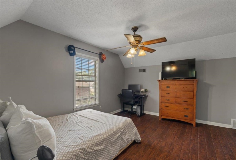 Spacious room featuring wood-finish flooring and a central ceiling fan with integrated lighting