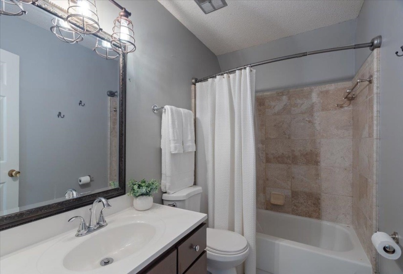 Bathroom featuring a dark wood-finish vanity with a white countertop and oval sink, chrome faucet, and framed mirror
