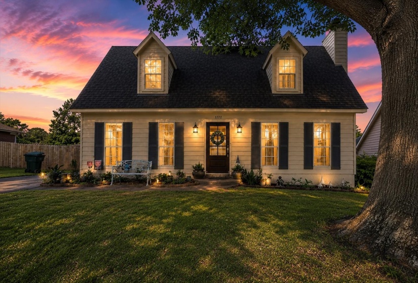 Dormered facade featuring a dark shingle roof, light-colored siding, and dark shutters