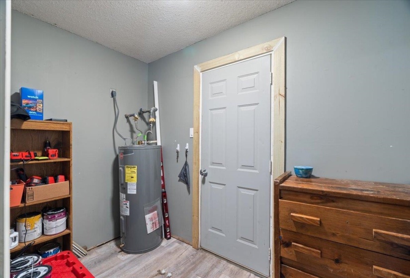 Utility area featuring a water heater, light gray walls, and wood-finish flooring