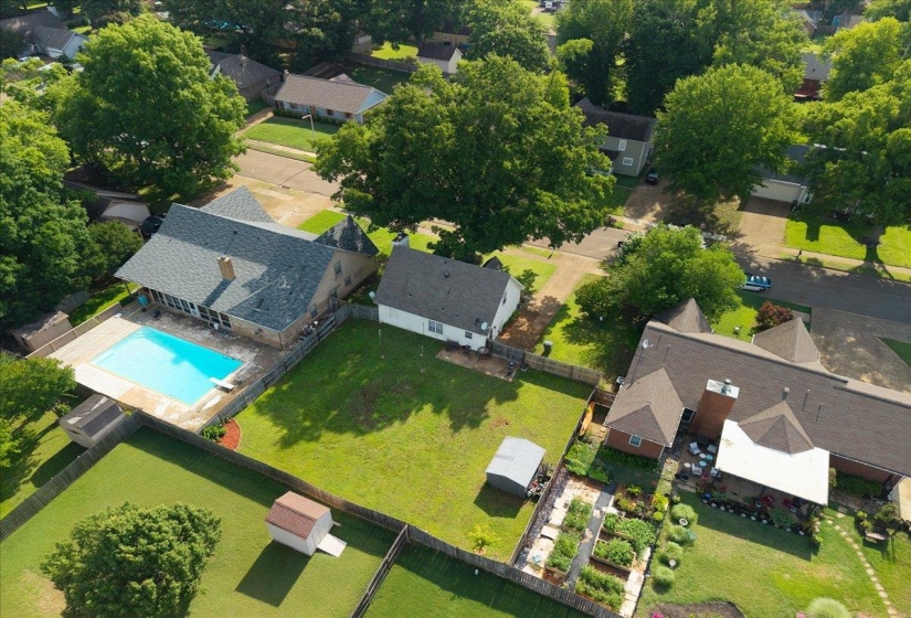 Expansive property featuring a swimming pool, multiple detached sheds, fenced perimeter, and a structured garden area