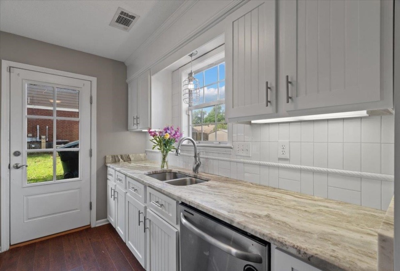 Kitchen workspace featuring light-toned countertops, a dual basin sink, and a modern faucet