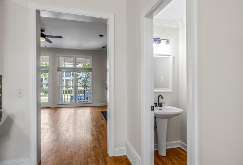 Pedestal sink with matte black faucet, wall-mounted mirror, and vanity light fixture