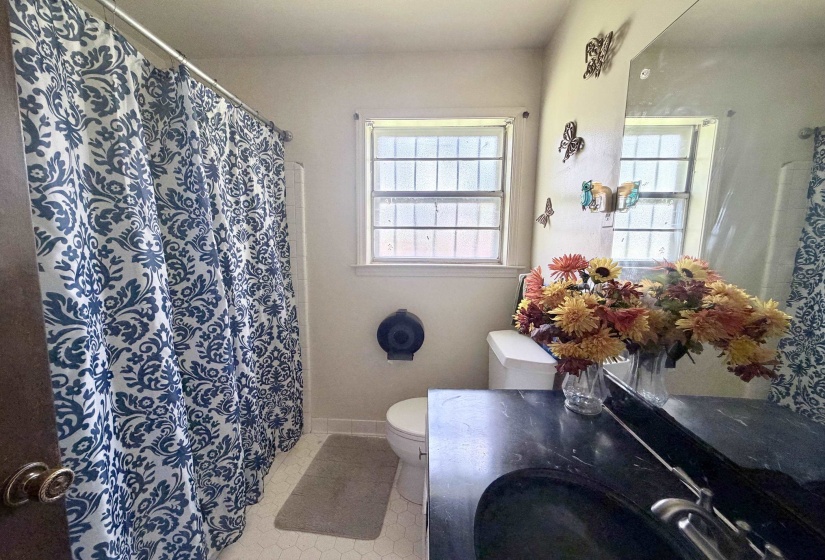 Bathroom featuring a black countertop with an integrated sink, a rectangular window with grid panes, and white hexagonal floor tiles