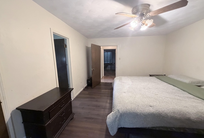 Interior room with wood-finish flooring, light-toned walls, and a ceiling fan with integrated lighting