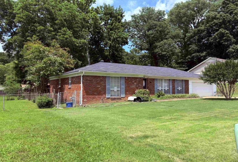 Traditional brick exterior with an attached garage, a dark shingle roof, and established landscaping
