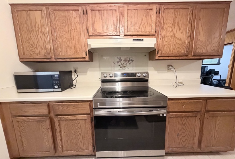 Kitchen featuring wood-finish cabinetry, white countertops, and a stainless steel electric range