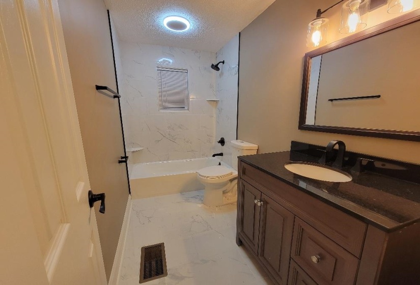 Contemporary bathroom featuring a dark wood-finish vanity with a dark countertop, an oval undermount sink, and a framed mirror