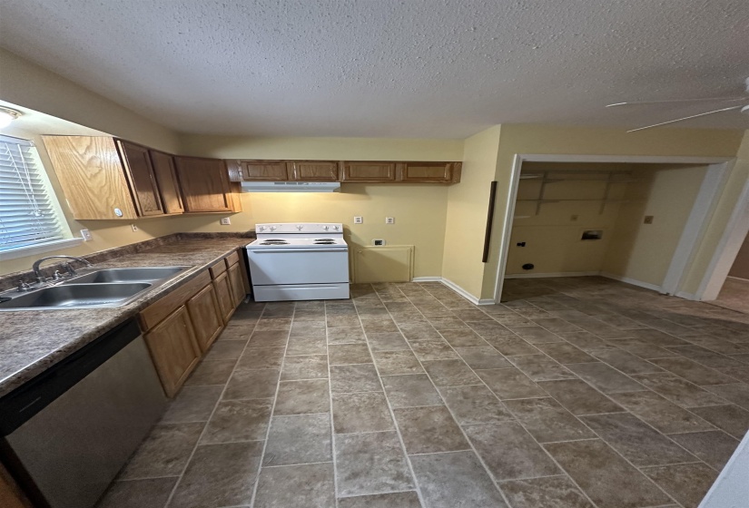 Kitchen featuring electric range, dishwasher, a sink, a textured ceiling, and under cabinet range hood