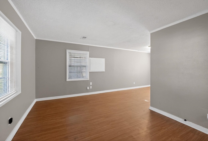 Spare room featuring crown molding, dark wood-type flooring, and a textured ceiling