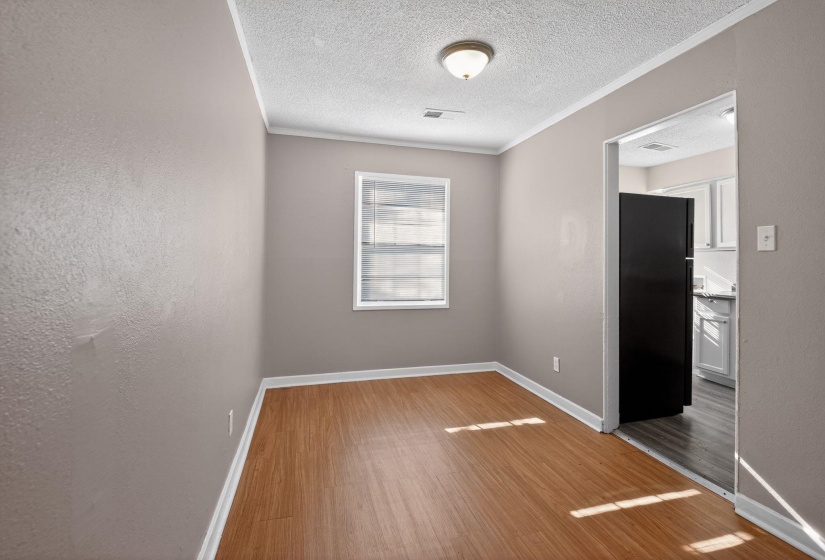 Spare room featuring a textured ceiling, wood finished floors, crown molding, and a textured wall
