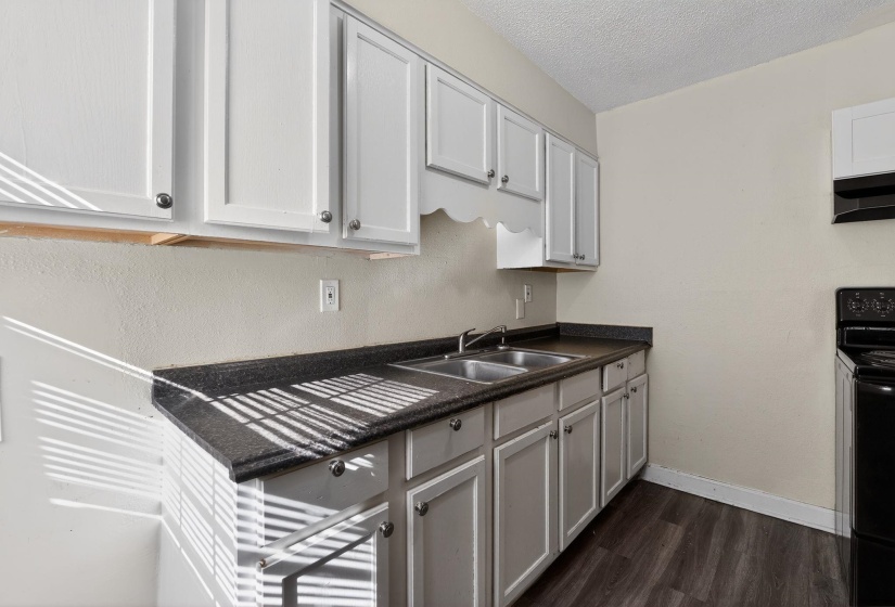 Kitchen with dark countertops, electric range, a textured ceiling, dark wood-style floors, and under cabinet range hood
