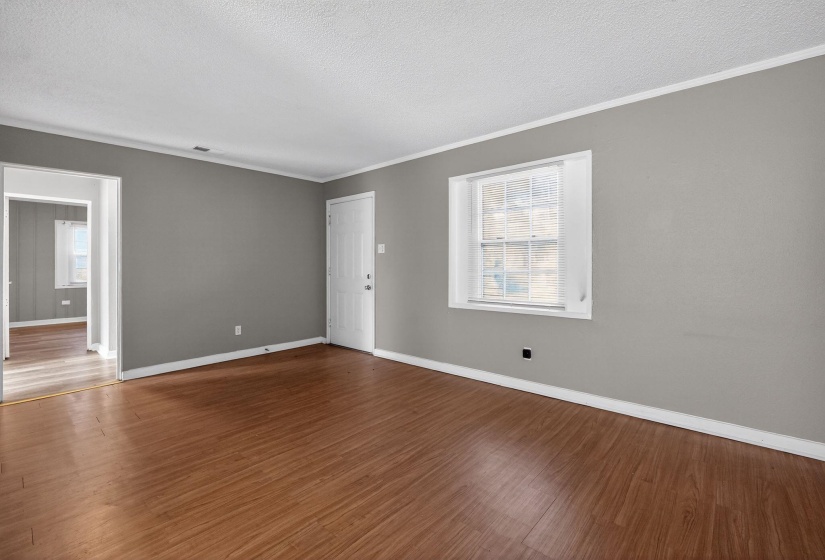 Unfurnished room with wood finished floors, a textured ceiling, ornamental molding, and plenty of natural light