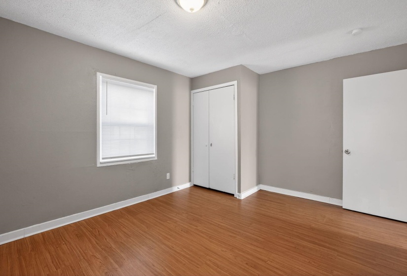 Unfurnished bedroom featuring a textured ceiling, wood finished floors, and a closet