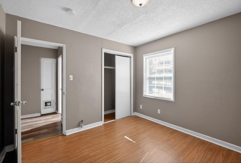 Unfurnished bedroom with a textured ceiling, a closet, and wood finished floors