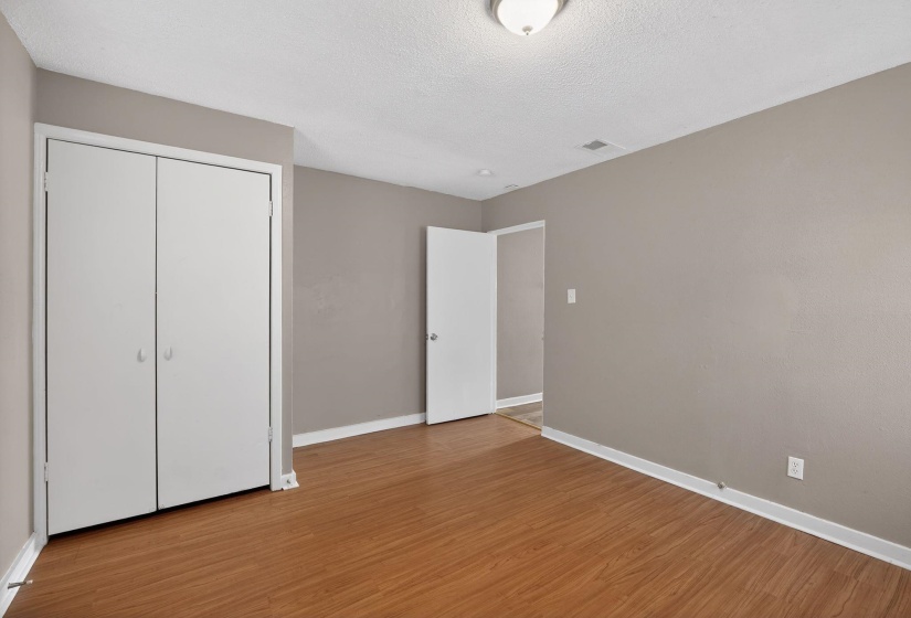 Unfurnished bedroom with a closet, light wood-style flooring, and a textured ceiling