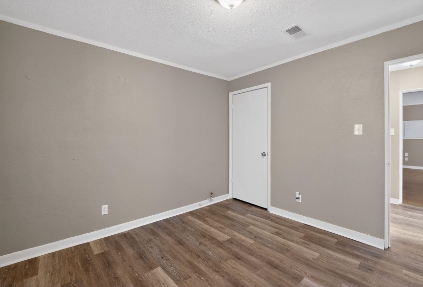Unfurnished bedroom with wood finished floors, ornamental molding, and a textured ceiling