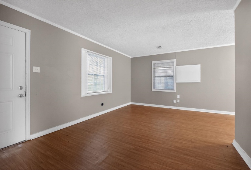 Empty room with dark wood finished floors, a textured ceiling, and crown molding