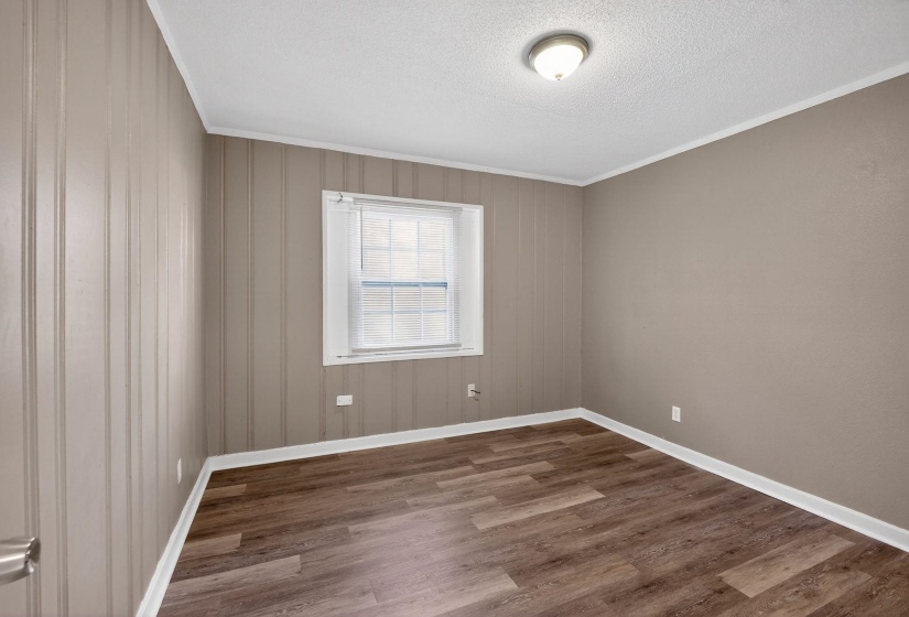 Unfurnished room featuring wood finished floors, a textured ceiling, and crown molding