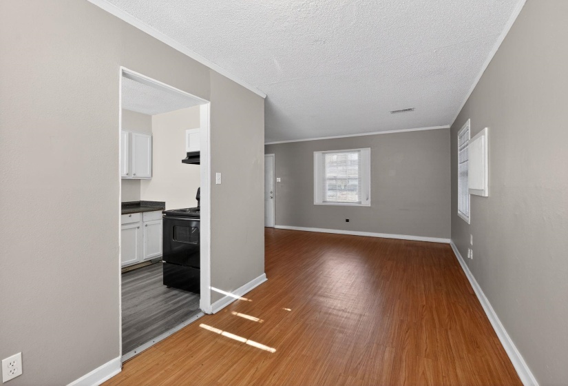 Unfurnished living room featuring a textured ceiling, light wood-style floors, and crown molding