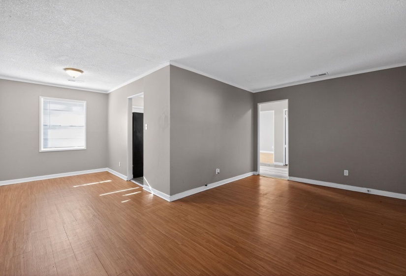 Empty room with wood finished floors, a textured ceiling, and crown molding