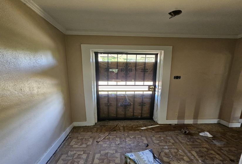 Entryway featuring a security screen door, patterned floor tiles, baseboard trim, crown molding, and textured walls