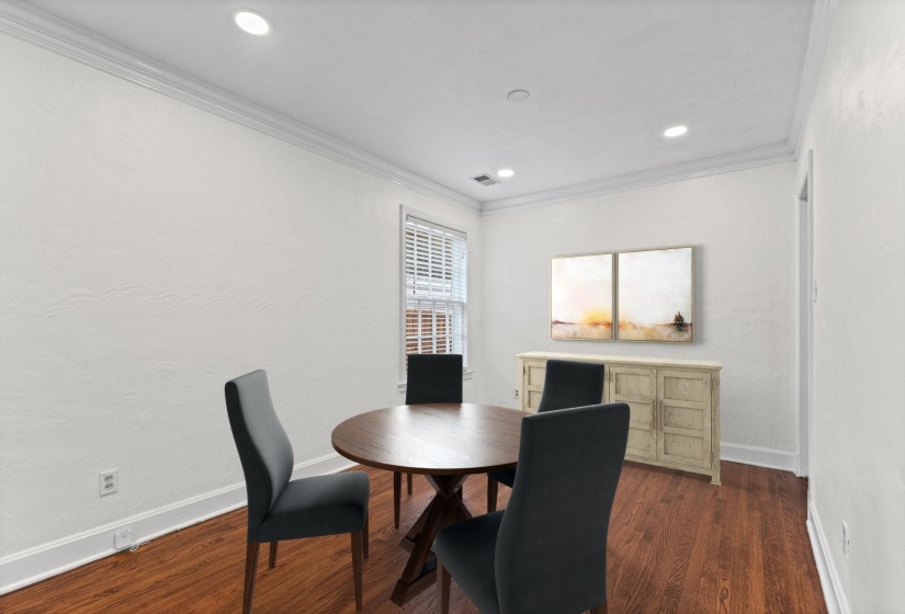 Spacious room featuring rich wood-finish flooring, white walls, and a window with blinds
