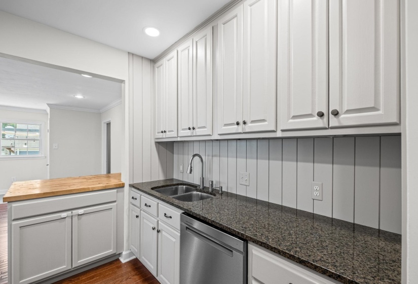 Modern kitchen featuring white shaker-style cabinetry with dark hardware, a double basin stainless steel sink, and a stainless steel dishwasher