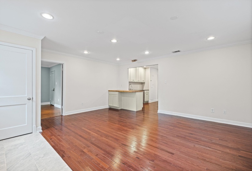 Open-concept living space featuring rich wood-finish flooring, recessed lighting, and a kitchen peninsula with a wood countertop