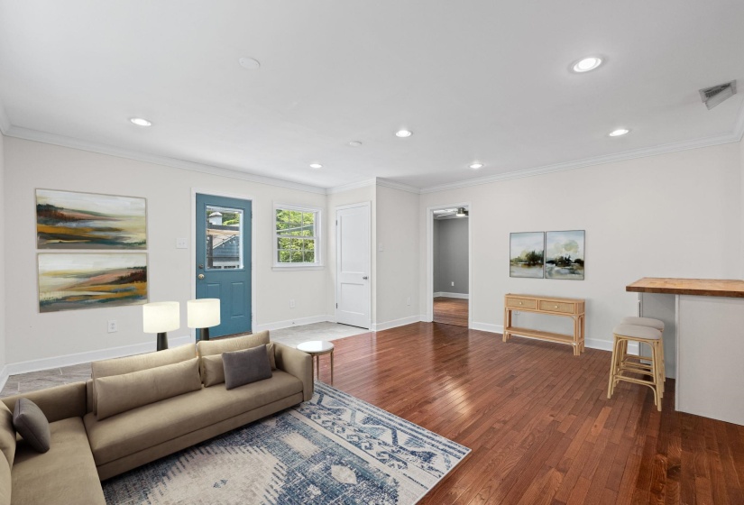Living area featuring recessed lighting, crown molding, wood-finish flooring, a breakfast bar with wood countertop, and a blue entryway door with glass paneling