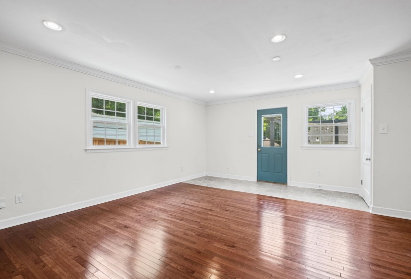 Spacious interior room featuring rich wood-finish flooring, crisp white walls, and recessed lighting