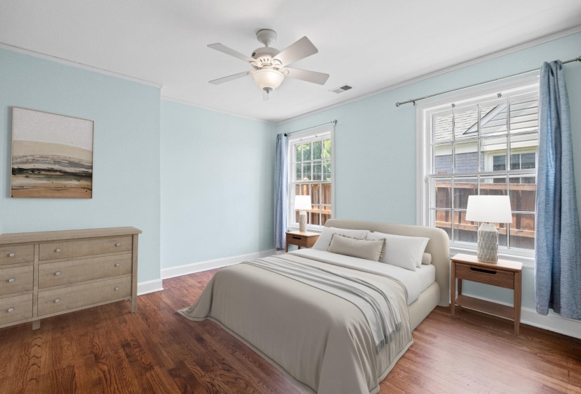 Bright room featuring wood-finish flooring, white crown molding, two large paneled windows, and a ceiling fan with integrated lighting