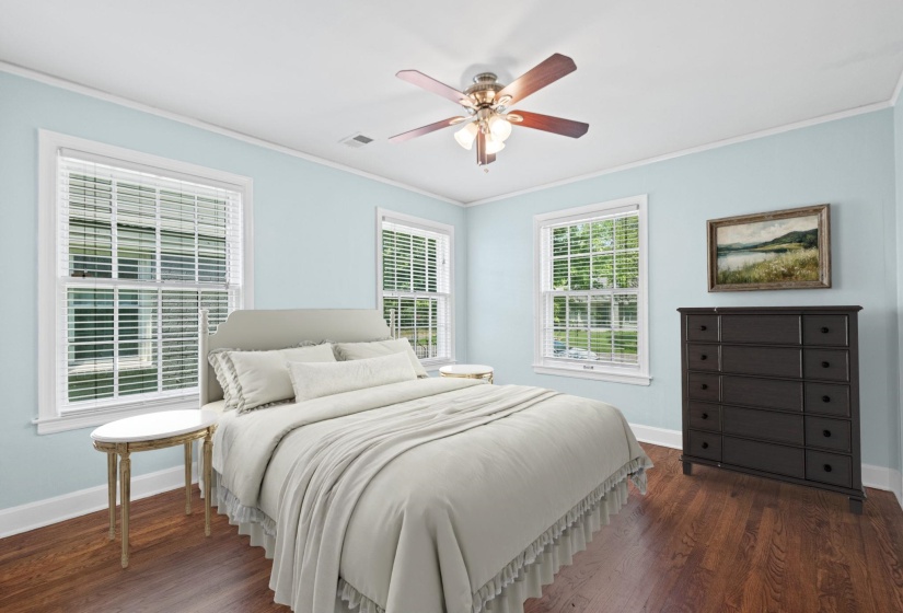 Room featuring light blue walls, white trim, wood-finish flooring, and multiple windows with blinds