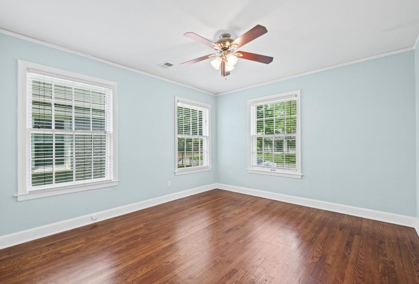 Room featuring rich wood-finish flooring, light blue wall paint, and white trim